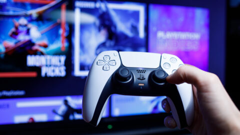 A PlayStation 5 DualShock remote is held up against a PlayStation Store backdrop.