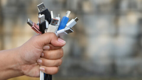 A hand gripping a large number of USB cords.